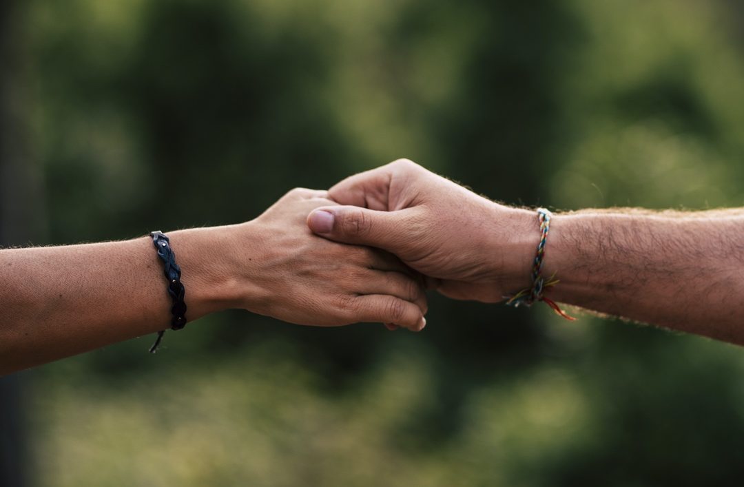 Concept of love and help each other people or relationship - close up of hands touching and holding or helping - green bokeh defocused background